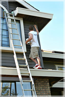 Painter working on exterior of house