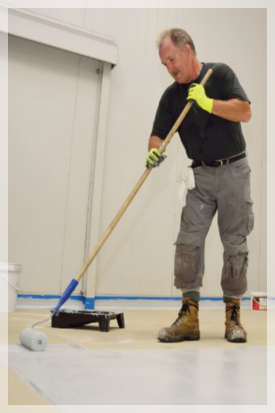 man applying an epoxy coating to a commercial floor 