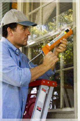 Man sealing window with caulk 